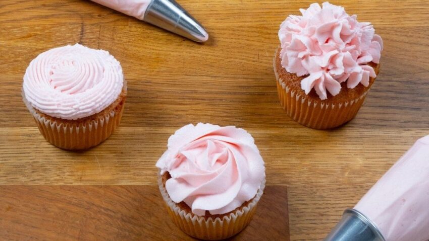 Tre cupcakes med rosa frosting, spritsade i olika mönster