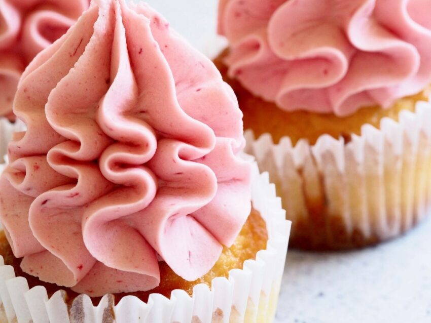 Närbild av muffins med höga virvlar av rosa smörkräm