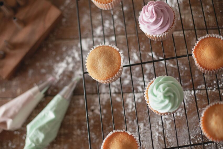 Cupcakes med platta toppar på ett galler, några dekorerade med frosting