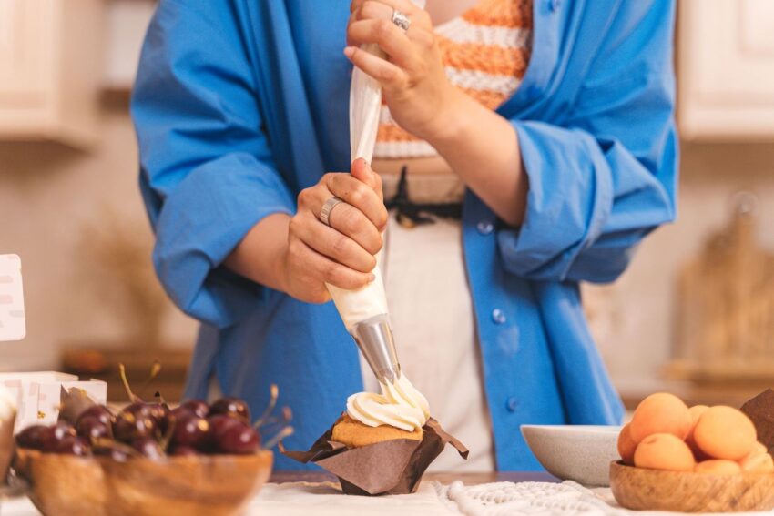 Person spritsar vit frosting på en cupcake med spritspåse